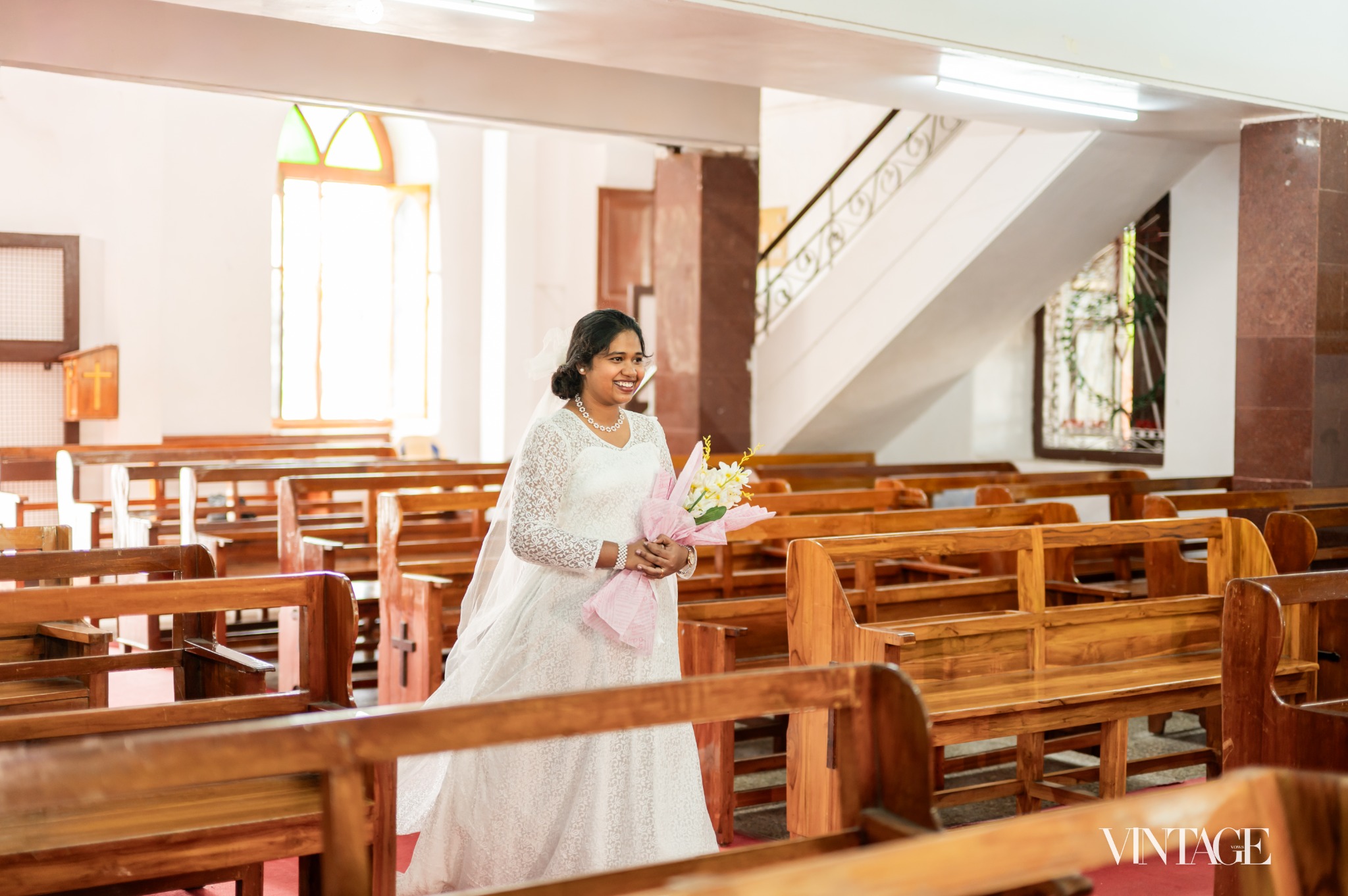 Betsy in a white dress holding a bouquet inside a church