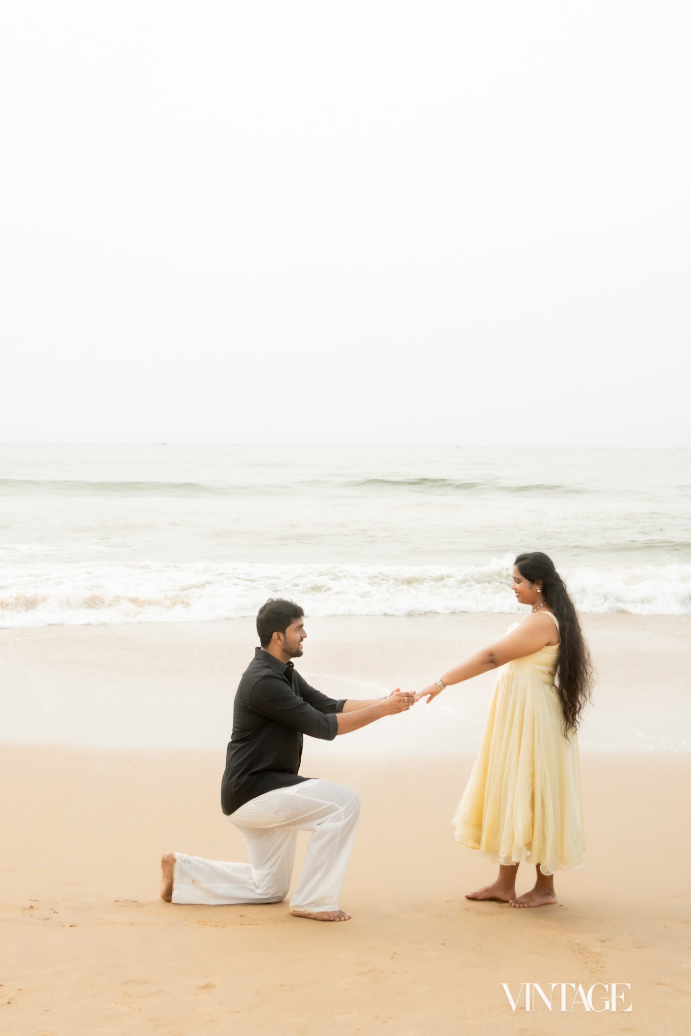 Ratan kneeling on the beach and holding Betsy’s hand